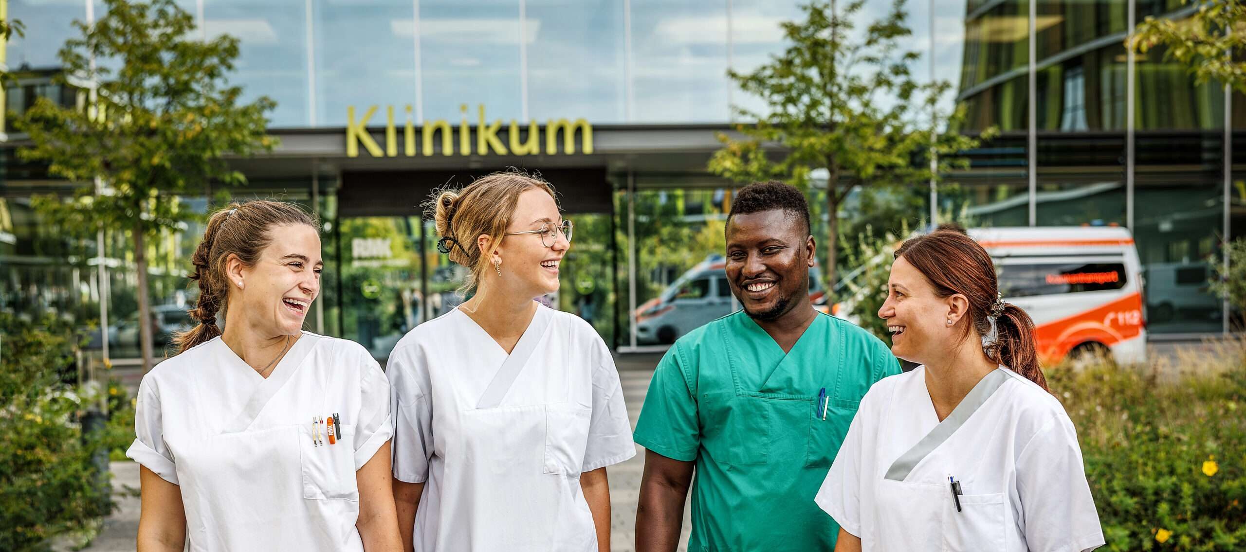 Vier Pflegefachpersonen lachend vor dem Hauptgebäude des Klinikums Winnenden
