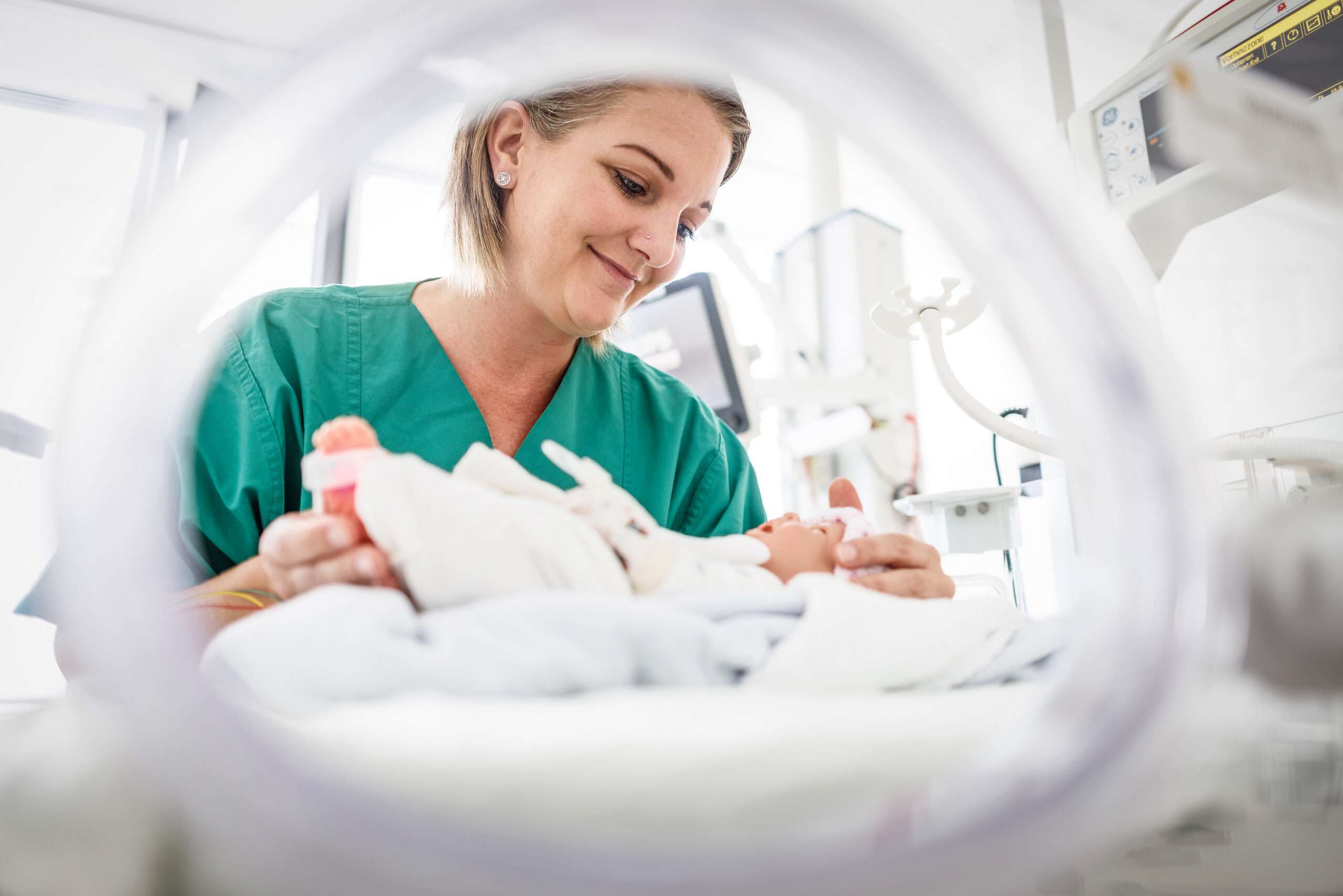 Pflegefachfrau am Inkubator, in dem ein Neugeborenes liegt
